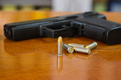 A black handgun on a table next to bullets