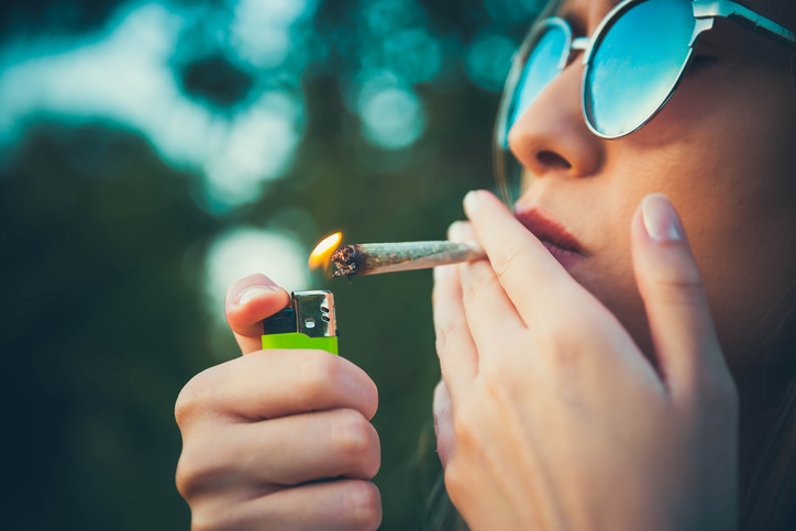 closeup of a teen lighting a marijuana cigarette