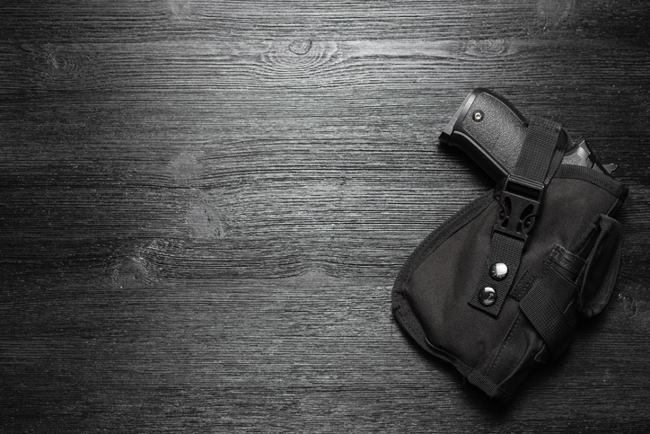 handgun in holster lying on a dark floor