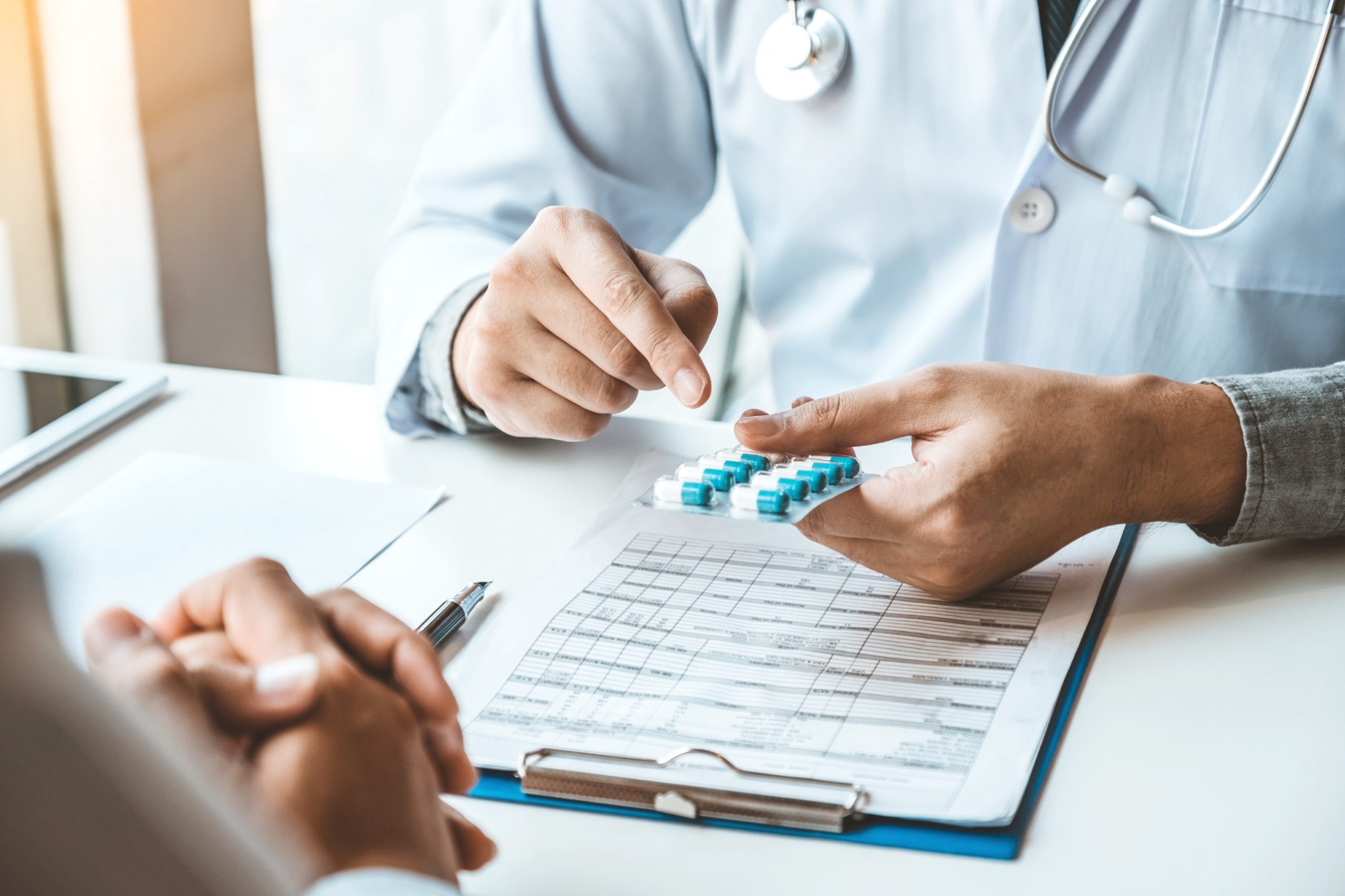 a pharmacist counts out medication for a patient over a clipboard