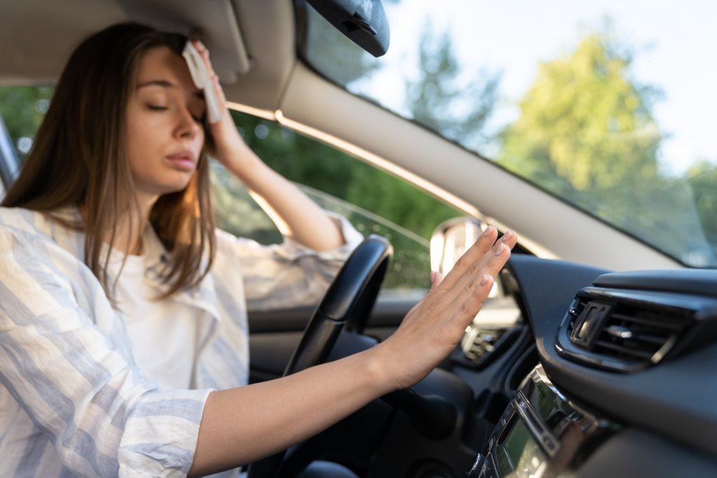 Woman in her car wipes sweat from her face during a heat wave.