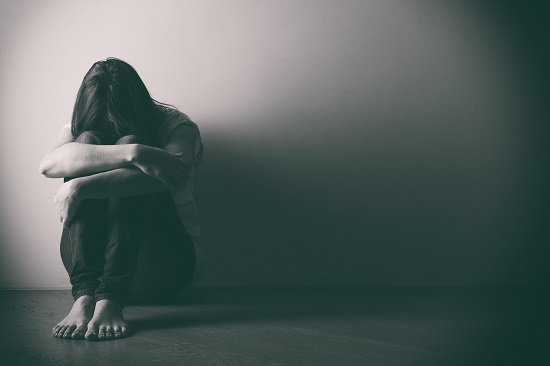 Teenager girl with depression sitting alone on the floor in the dark room. . Black and white photo