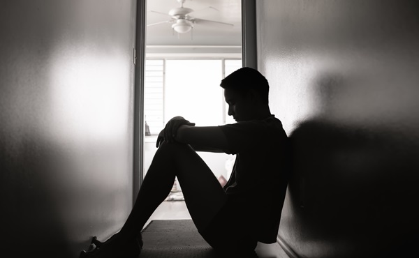 Sad man sits alone in a hallway.